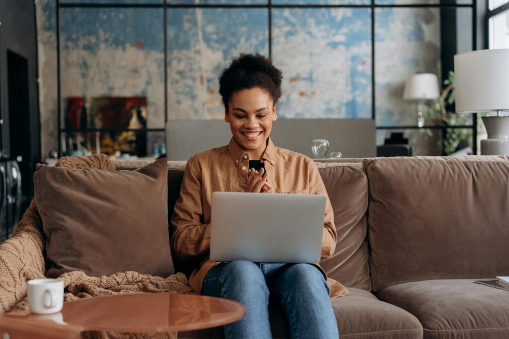 Woman sitting on her couch working on her laptop, representing the medical billing Industry trends of working remotely.  | medical billing industry trends