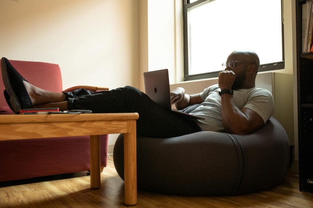 Man sitting in a bean bag chair with feet up, working on his laptop for medical billing outsourcing. | medical billing outsourcing