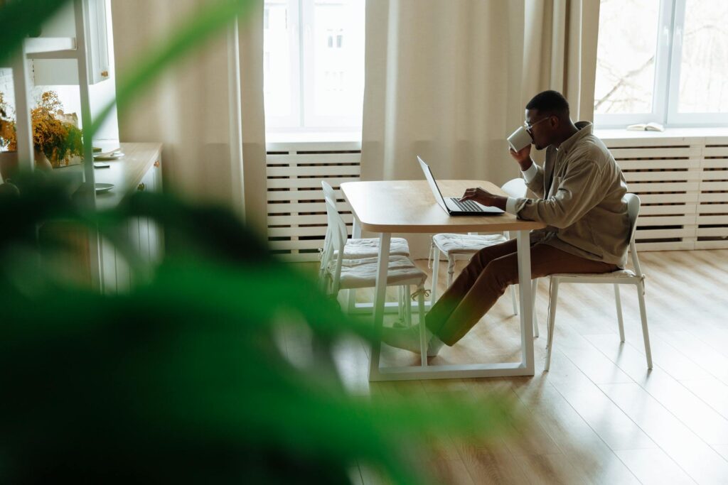man drinking from mug while working on a laptop | medical billing outsourcing