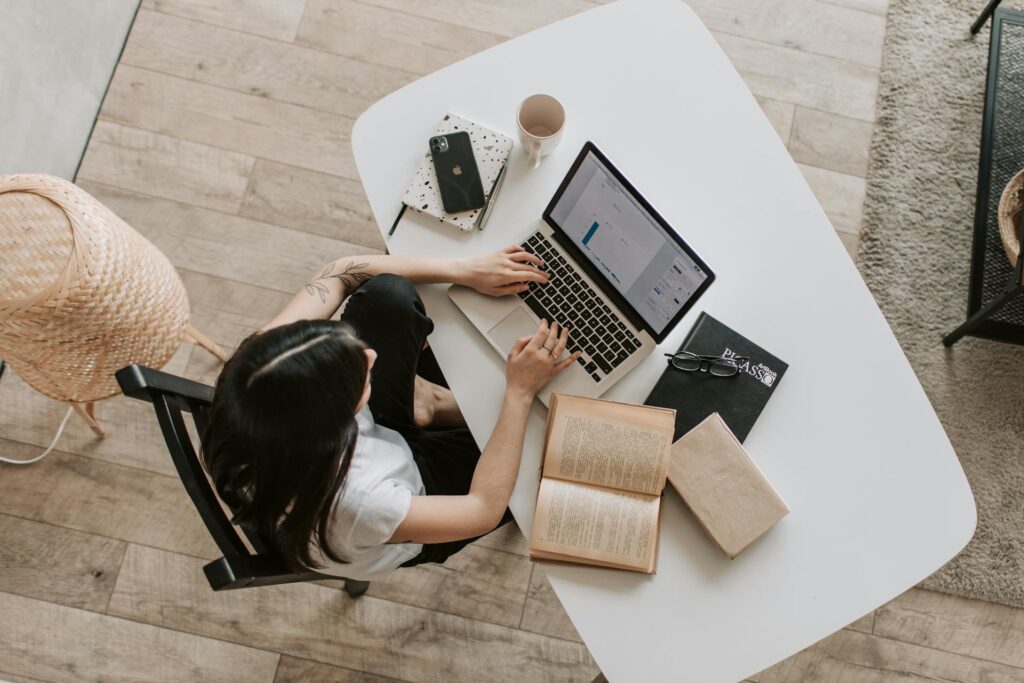 Aerial view of woman in white shirt on laptop working from home office, looking into medical billing industry trends. | medical billing industry trends